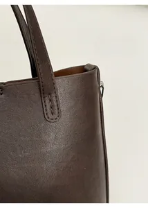 Détail du sac seau en cuir marron foncé montrant les bordures et les coutures de précision