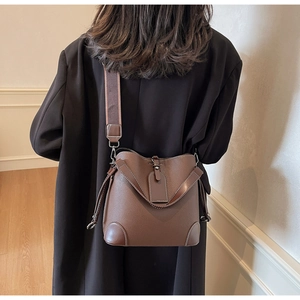 Detail of dark brown pebble leather bucket bag with wide strap and reinforced corners