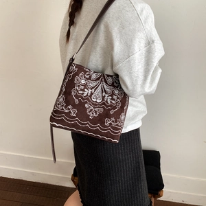 Détail d'un sac seau vintage marron avec broderies florales complexes sur le suède doux
