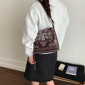 Détails de broderie sur un sac seau bohème marron vintage porté par un mannequin