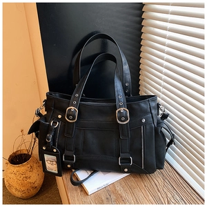 Dettaglio ravvicinato di una borsa tote retrò in ecopelle nera con fibbie argentate e stile punk