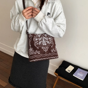 Sac bandoulière marron en suédine avec broderie bohème présenté dans un décor intérieur