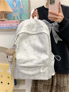 White canvas backpack with marble pattern, embroidery, and cute plush bear accessory