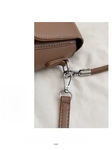 Détail du fermoir à ressort argenté et de l'anneau en D sur sac en cuir marron foncé