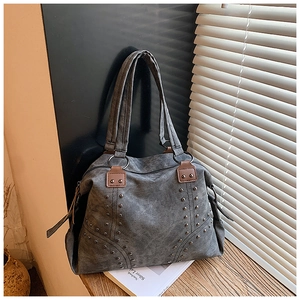 Détail du sac cabas en toile grise avec clous métalliques et fixations en cuir marron