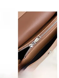 Détail d'une fermeture éclair argentée et de cuir grainé marron sur un sac bandoulière