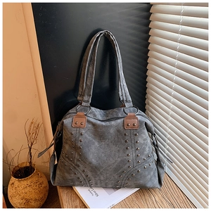 Detail view of retro gray canvas tote bag with V-shaped metal studs and leather straps