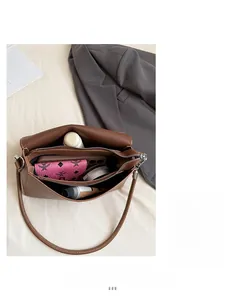 Détail du sac à bandoulière en cuir marron montrant les compartiments intérieurs