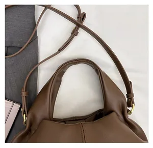 Detail of brown leather bag with gold hardware buckles and adjustable shoulder strap