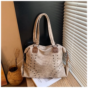 Détail du sac cabas vintage beige avec des rivets métalliques et des anses en cuir marron