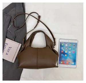 Detail view of dark brown dumpling crossbody bag with pleats and thin shoulder straps