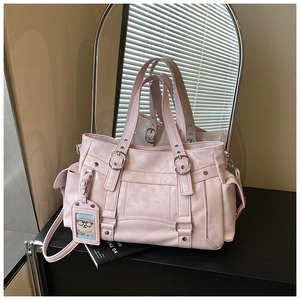 Dettaglio della borsa tote rosa con borchie argentate, fibbie e ciondolo a forma di orso