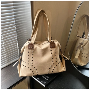Détail du sac cabas beige vintage avec clous métalliques et doubles anses sur table noire