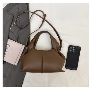 Detailed view of brown matte leather dumpling bag with adjustable strap and top handle