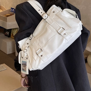 Dettaglio borsa messenger bianca in pelle con fibbie argentate e ciondolo a forma di orso