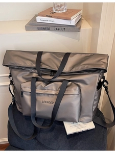 Minimalist metallic taupe nylon tote bag with shoulder strap on a blue corduroy chair