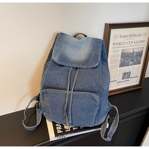Detail of vintage blue denim backpack with drawstring closure and front zipper pocket