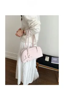 Detail view of pink leather shoulder bag with a star charm accessory on a white sweater