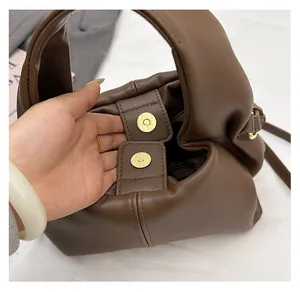 Detail of dark brown lychee textured bag with gold magnetic snap and fine stitching