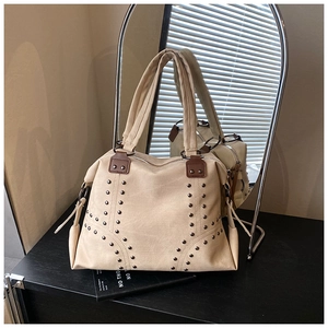 Détail du sac cabas en toile beige avec rivets argentés et poignées en cuir marron