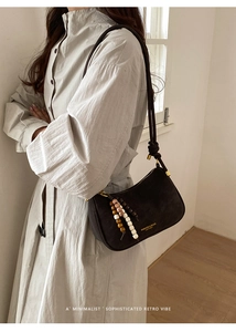 Détail du sac baguette en daim marron foncé avec glands en perles colorées et texte doré