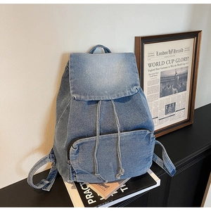 Detailed view of vintage washed denim texture and flap drawstring closure on the backpack