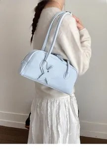 Detail of light blue leather baguette bag with star charm and side stitching details