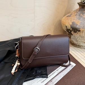 Détail du sac en cuir grainé marron avec breloque en perles de bois et boucle argentée