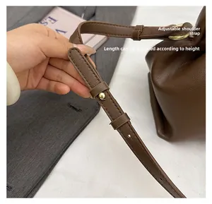 Detail of adjustable shoulder strap with golden rivet on dark brown leather cloud bag