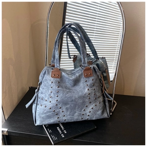 Détail du sac cabas en toile lavée bleue avec rivets et poignées en cuir marron