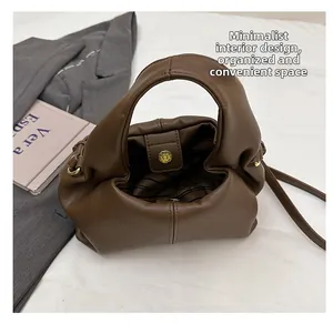 Detail view of brown cloud bag with striped lining, magnetic buckle and shoulder strap