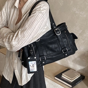 Dettaglio di una borsa tote nera vintage con fibbie metalliche e ciondolo porta carte