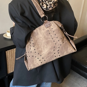Détail d'un sac cabas marron vintage avec rivets métalliques et texture mate
