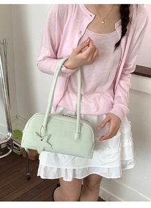 Mint green leather shoulder bag with star charm worn by model in minimalist indoor setting