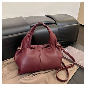 Detail of burgundy cloud bag with pleated leather texture and gold metal hardware