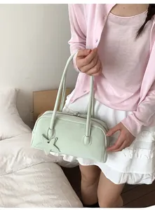 Detail of mint green shoulder bag featuring a star charm and minimalist zip closure