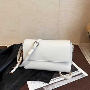 Détail du sac à main en cuir grainé blanc avec rabat et pendentif de perles
