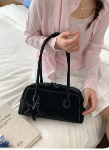 Close-up of black retro shoulder bag with white contrast stitching and star charm detail