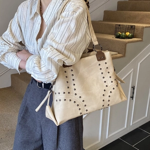 Détail du sac cabas crème avec des rivets métalliques élégants et une bandoulière renforcée
