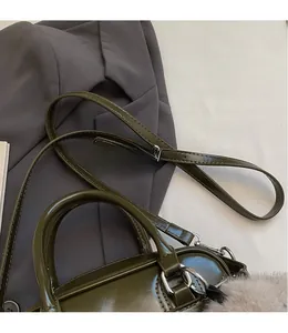 Détail du sac bowling vert foncé avec bandoulière lisse et charm en peluche doux