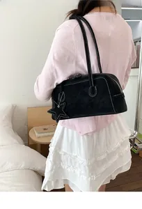 Close-up of black Boston bag with white stitching detail and star-shaped charm accessory