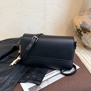 Détail du sac à main noir en cuir grainé avec fermoir argenté et breloque perlée