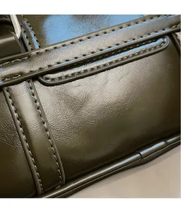 Gros plan détaillé du cuir verni vert olive avec des coutures fines et des boucles métalliques