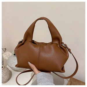Detail view of caramel brown dumpling bag with ruched leather texture and top handle