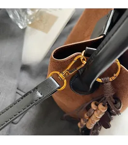 Détail du sac seau vintage en daim avec ferrures dorées et attache de bandoulière en cuir
