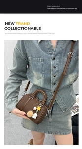 Detail of dark brown mini Boston bag with plush ball charm on denim outfit