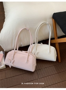 Detail of pink and white faux leather baguette bags with star pendants on wooden floor