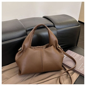 Detail view of smooth dark brown leather texture and soft draped folds on the handbag