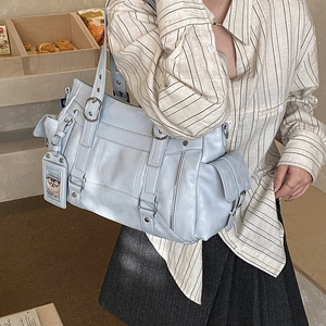Dettaglio della borsa tote azzurra con tasche utility e ciondolo a forma di orsetto