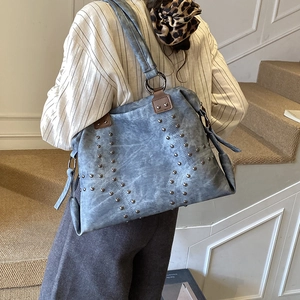 Détail du sac cabas bleu gris montrant les rivets métalliques et le cuir mat vintage